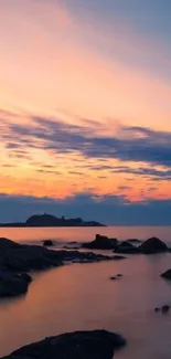 Sunset over ocean with rocks and colorful sky on mobile wallpaper.