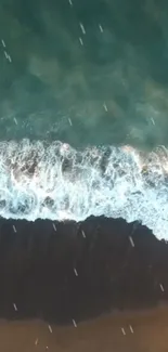 Aerial view of ocean waves crashing onto a sandy shore, creating a serene blue-green scene.