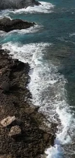 Aerial view of rocky coastline with teal ocean waves.