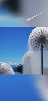 Dandelion water fountain against a bright blue sky.