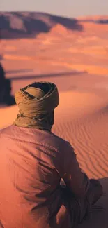 Person sits in serene desert with golden dunes.