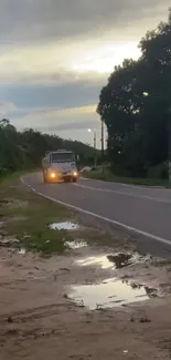 Truck driving on a rural road at dusk with a serene landscape backdrop.