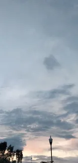 Serene evening sky with clouds and lamp silhouette.