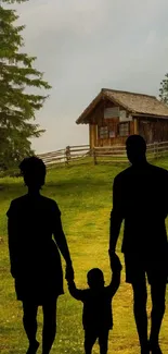 Family silhouette on green countryside with rustic cabin backdrop.