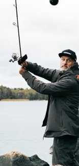 Man fishing by rocky lake in nature.