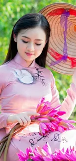 Woman in traditional dress holding pink flowers with a green background.