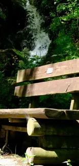 Wooden park bench in a lush forest with a waterfall.