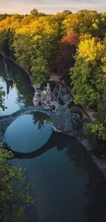 Aerial view of a forest bridge reflected in calm waters.