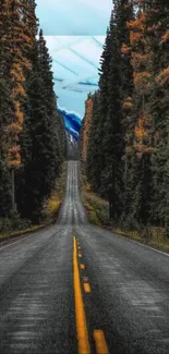 Long road through dense forest with mountains in the background.