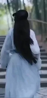 Person in long dress walking up stone steps in a serene forest.