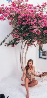 Woman sitting under pink blooms with cats in tranquil garden.