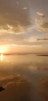 Golden sunset over a tranquil ocean with clouds and reflections.