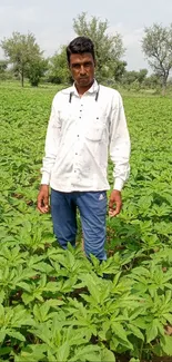 Man standing in lush green farm with blue sky and trees.