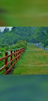 Lush green path with a wooden fence and trees on a serene mobile wallpaper.