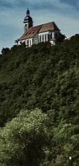 A serene chapel on a green, lush hillside under a blue sky.