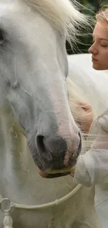 Calm interaction between a woman and a white horse in nature.