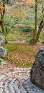 Japanese Zen garden with stones and autumn leaves in tranquil setting.