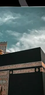 Kaaba under a calm teal sky with clouds