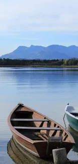 Wooden boat on calm lake with mountain background.