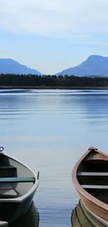 Two boats on a serene lake with mountains in the background.