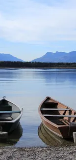 Lake with wooden boats and mountains under a clear blue sky.