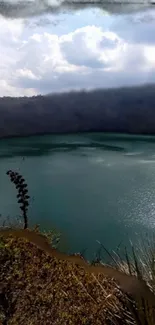 Tranquil lake surrounded by hills under a cloudy sky wallpaper.