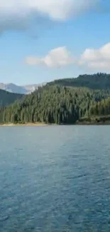 Serene lake with forested hills under a blue sky.