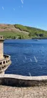 Serene lake with stone tower and green hills under a blue sky.