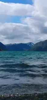 Tranquil lake with mountains under cloudy sky.