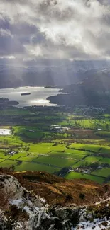 Stunning view of lake, fields, and mountains with dramatic clouds overhead.