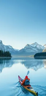 Kayaker on a serene mountain lake with snow-capped peaks.