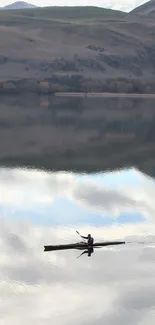 Kayak gliding on serene lake with mountain reflections.