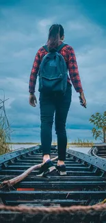 Traveler walking on wooden path under dramatic cloudy sky.