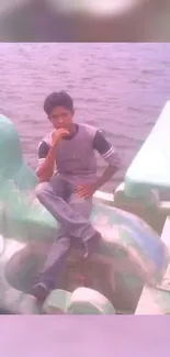 Man sitting on a green paddle boat on a quiet lake.