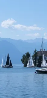 Peaceful lake with sailboats and mountain backdrop.