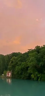 Lakeside sunset with pink sky and green trees reflected on water.