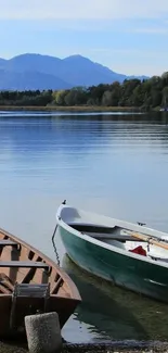 Serene lake with wooden boats and mountain backdrop.