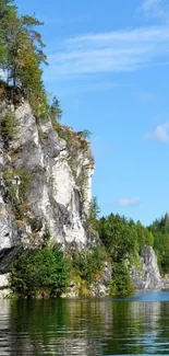 Lakeside cliff with trees under a clear blue sky.