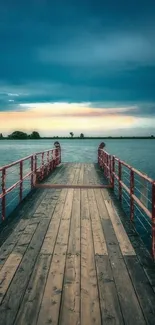 Serene dock extending into lake with a cloudy sky and sunset in the background.