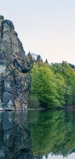 Serene lakeside forest with rocky formations and green trees.