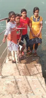 Four friends on stairs by a calm lake.