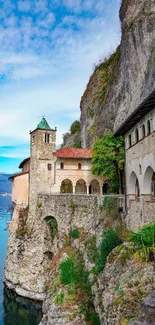 Lakeside monastery by a rocky cliff under a clear blue sky.