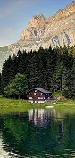 Lakeside cabin surrounded by trees with mountain backdrop and lake reflection.