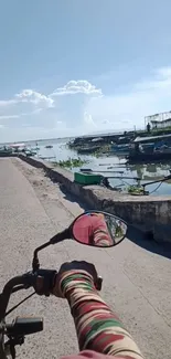 Motorcycle view of serene lakeside with blue sky.