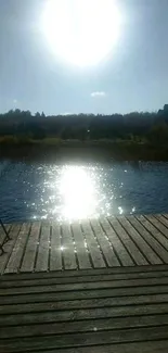 Serene lakeside scene with sunlight on the water and wooden deck.