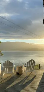 Two chairs overlooking a serene sunrise on a lake.