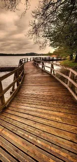 Serene wooden boardwalk by a calm lakeside under a cloudy sky.