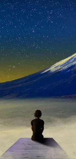 Person sitting under starry sky beside mountain.