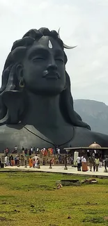 Statue amidst green fields under a cloudy sky.