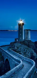 Lighthouse on rocky coast against a blue night sky, illuminating the serene dusk.